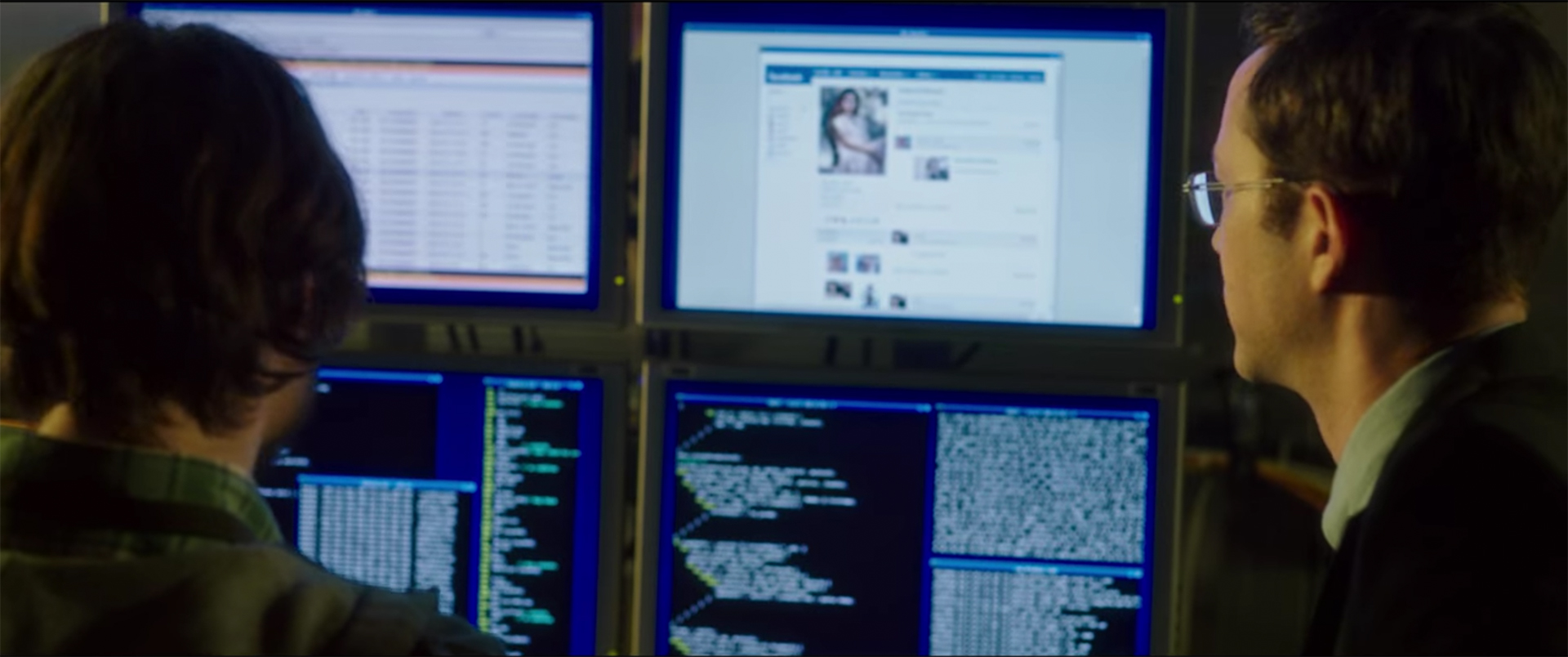 Snowden und ein Arbeitskollege blicken auf eine Wand voller Monitore